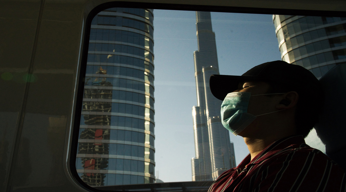  In this April 26, 2020, file photo, a commuter wearing a face mask to help curb the spread of the coronavirus, sleeps aboard the driverless Metro as it passes the Burj Khalifa, the world's tallest building, in Dubai, United Arab Emirates. (AP Photo/Jon Gambrell, File)