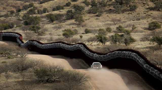 This March 2, 2019 photo shows a Customs and Border Control agent patrols on the US side of a razor-wire-covered border wall along the Mexico east of Nogales, Ariz. (AP Photo/Charlie Riedel,File)