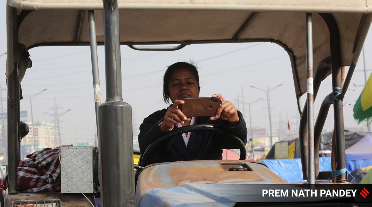 A woman farmer watching news on mobile phone at Ghazipur border on Feb 8, 2021 (Express photo by Prem Nath Pandey)