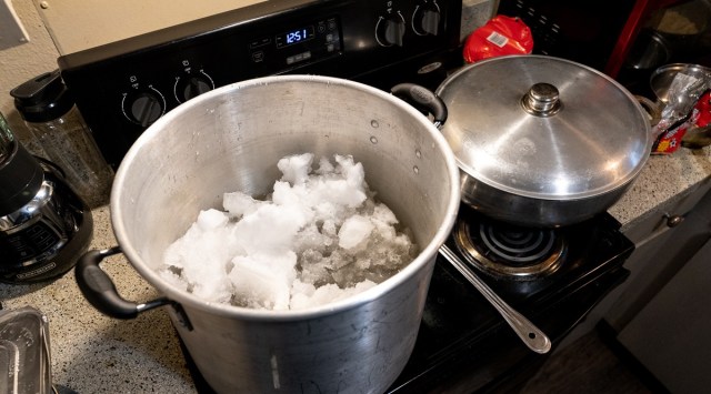 A famly melts snow on their stovetop to get water in Austin, Texas, Feb. 17, 2021. (Ilana Panich-Linsman/The New York Times)
