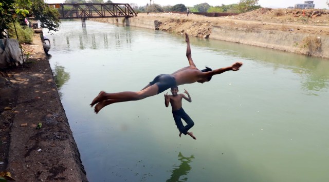 Kids enjoy a nice afternoon swim to get a respite from scorching summer heat at the canal near Janata Vasahat near Parvati. (Express Photo by Pavan Khengre)