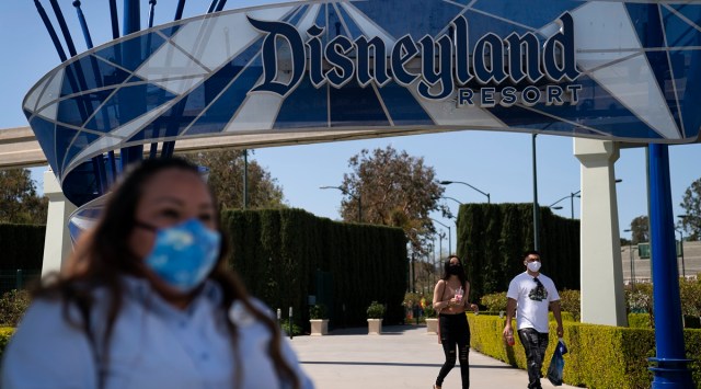 A woman with a face mask waits to cross the street outside Disneyland Resort in Anaheim, California. (Photo: AP)