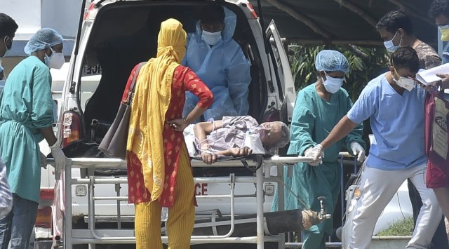 Health workers help a COVID-19 patient during admission at a hospital, as coronavirus cases spike in Kolkata, Friday, April 30, 2021. (PTI Photo/Swapan Mahapatra)