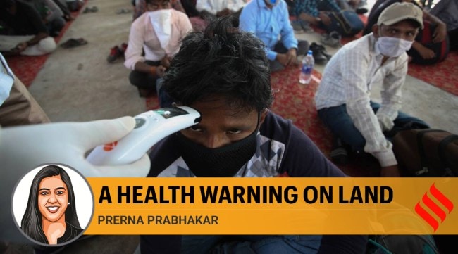 A doctor checks the temperature of a migrant worker who arrived from New Delhi, outside Allahabad bus station in April 2020. (Express Photo: Ritesh Shukla)