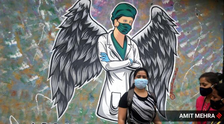 Women wearing masks walk past a mural in New Delhi on Friday, April 16, 2021 (Express photo By Amit Mehra_