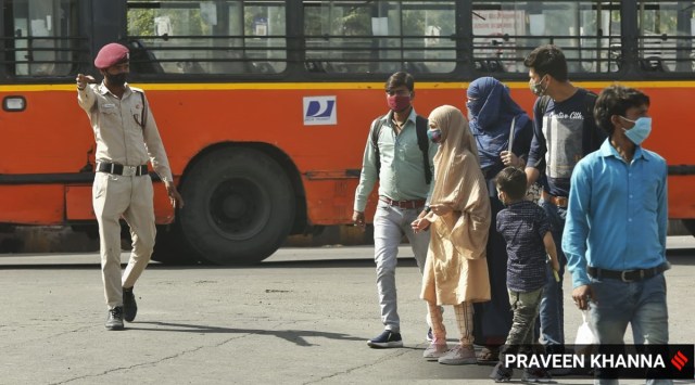 Civil Defence volunteers direct travellers at Anand Vihar interstate bus terminal in New Delhi on April 2, 2021. (Express Photo: Praveen Khanna)