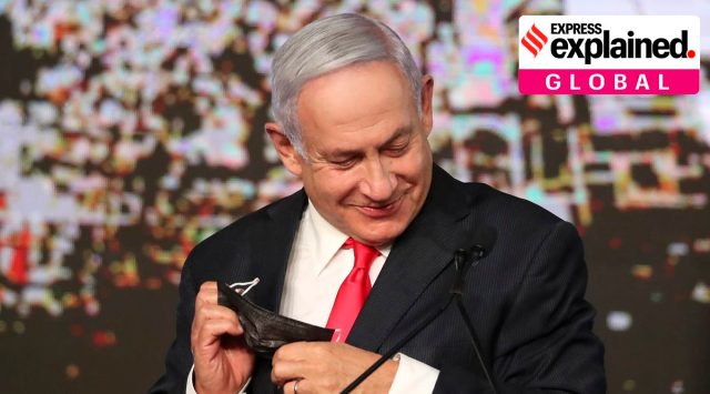 Israeli Prime Minister Benjamin Netanyahu takes off his face mask as he addresses his supporters after the first exit poll results for the Israeli parliamentary elections at his Likud party's headquarters in Jerusalem, Wednesday, March 24, 2021. (AP Photo/Ariel Schalit)