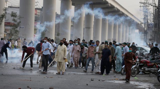 Angry supporters of Tehreek-e-Labiak Pakistan throw stones towards police firing tear gas to disperse them, at a protest against the arrest of their leader Saad Rizvi, in Lahore, Pakistan, Monday, April 12, 2021. (AP Photo/K.M. Chaudary)