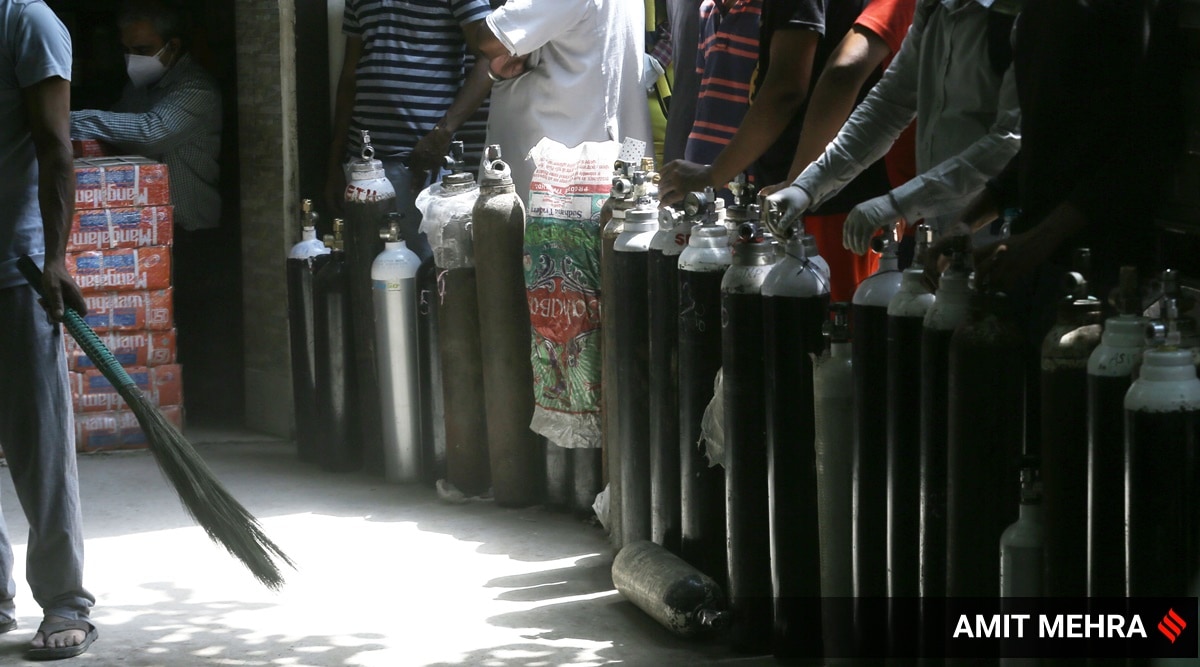 Family members of COVID-19 patients wait to fill their empty cylinders with medical oxygen outside an oxygen filling centre, at Bhogal, in New Delhi (Express Photo/Amit Mehra)