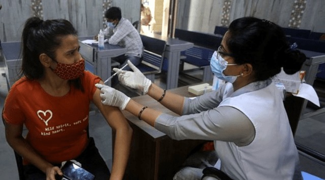 A woman receives her first dose of a Covid-19 vaccine at a school in New Delhi on Monday. (Express Photo By Amit Mehra)