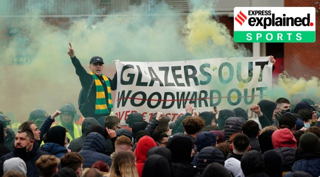 Manchester United fans let off flares and hold a banner as they protest against the Glazer family before their English Premier League soccer match against Liverpool at Old Trafford stadium in Manchester, England, Thursday, May 13, 2021. (AP Photo/Jon Super)