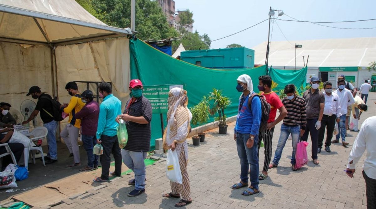 Reletives of Patients admitted in Jumbo Covid Hospital stand in a line to deliver necessary items to the patients on Saturday. (Express photo by Ashish Kale)