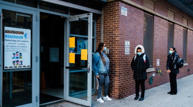 Students wait outside the Bronx School for Law where in-person learning resumed for students who opted for hybrid learning. (Photo: The New York Times)