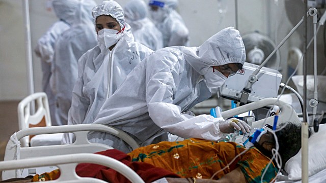 A health worker tries to adjust the oxygen mask of a patient at the BKC jumbo field hospital, one of the largest COVID-19 facilities in Mumbai. (AP Photo/File)