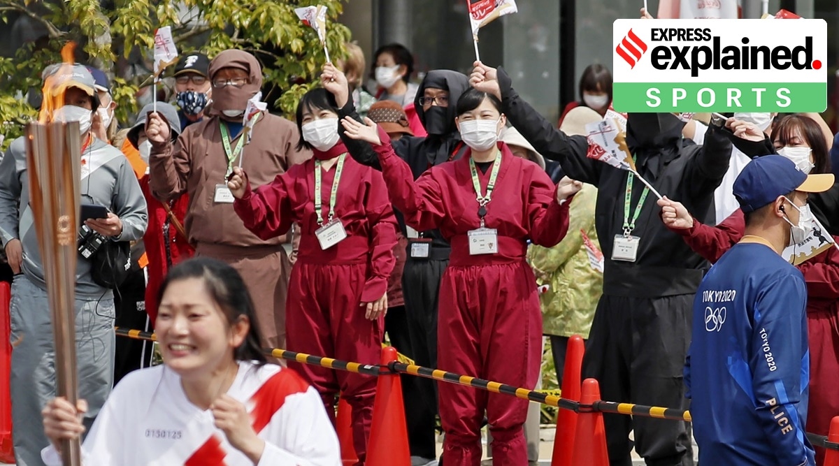 Spectators wearing face masks and ninja outfits, cheer a torchbearer carrying the Olympic torch in Iga, Mie prefecture, central Japan, Thursday, April 8, 2021. (AP)