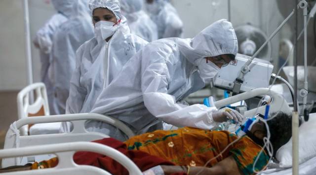 A health worker tries to adjust the oxygen mask of a COVID-19 patient at the BKC field hospital in Mumbai. (Photo: AP/File)