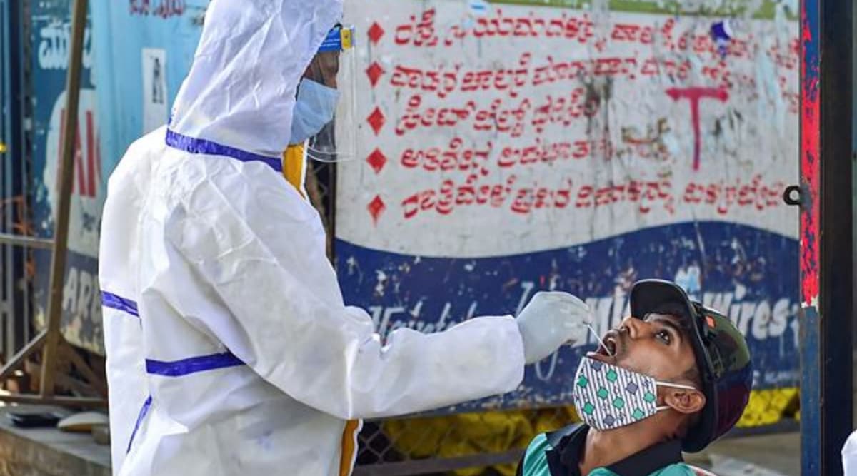 A health worker collects swab sample from a person for COVID-19 test, at a market in Bengaluru. (PTI Photo)