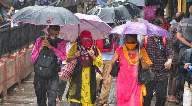 People hold umbrellas while cross the road at CST, in Mumbai, on Tuesday. (PTI)