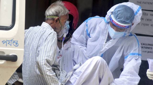 A health worker helps a COVID-19 patient during his admission at a state government run hospital in Kolkata. (PTI)