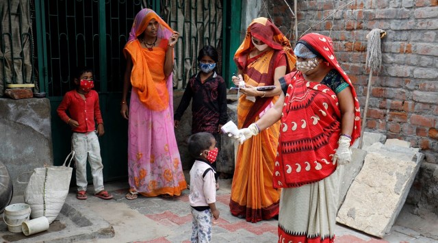 A healthcare worker checks the temperature of a child during a door-to-door surveillance on the outskirts of Ahmedabad. (Reuters)