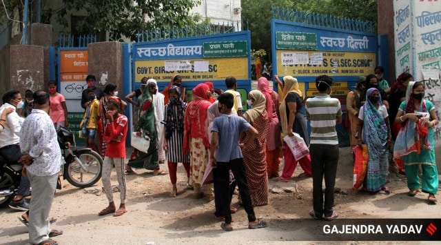A queue outside a ration distribution centre in Sangam Vihar on Thursday. (Express Photo: Gajendra Yadav)