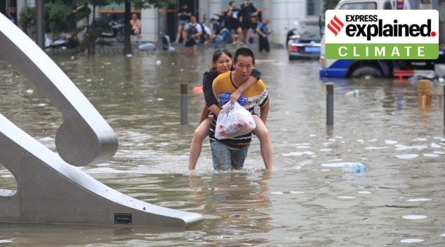 A man carrying a woman wades through a flooded road following heavy rainfall in Zhengzhou, Henan province, China July 21, 2021. (Reuters)