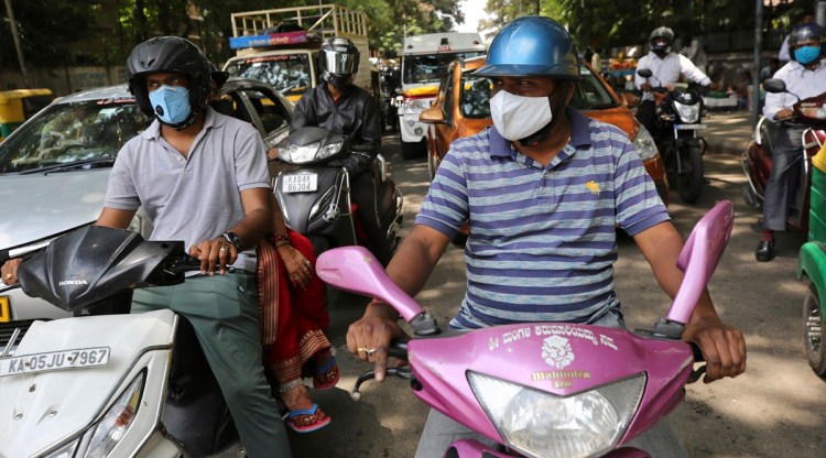 Motorists wearing face masks as a precaution against the coronavirus wait at a traffic intersection in Bengaluru. (AP)