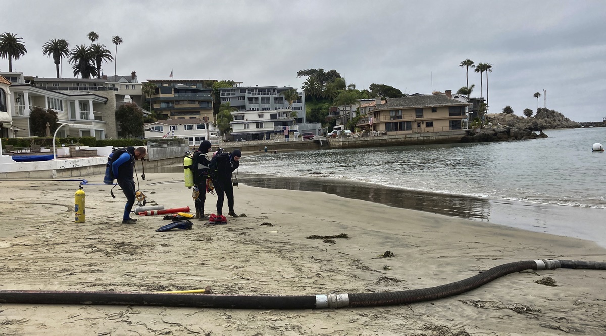 Divers get ready to enter the harbor to help suction and filter out algae in Newport Beach