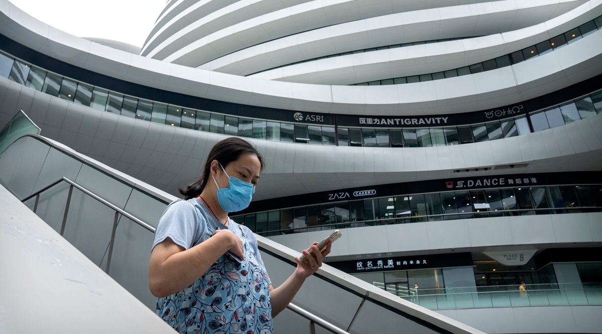 A woman wearing a face mask to protect against Covid-19 walks at a shopping and office complex in Beijing, Tuesday, July 27, 2021. (AP)
