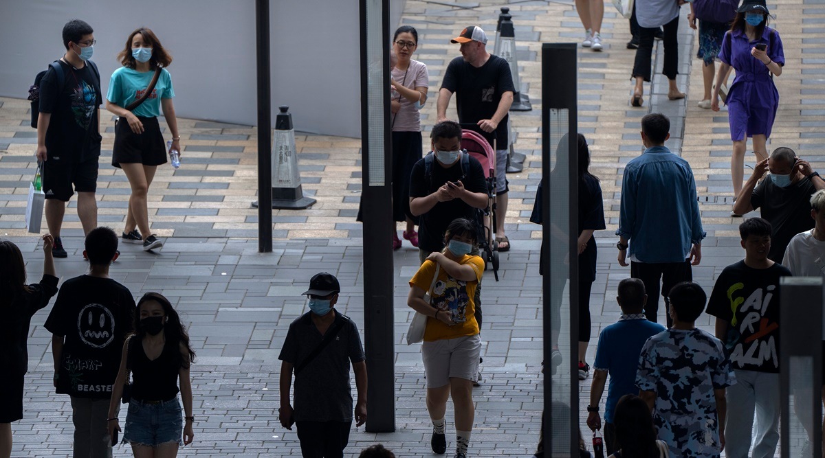People wearing face masks to prevent the spread of COVID-19 at a shopping mall in Beijing. (AP Photo/Mark Schiefelbein)
