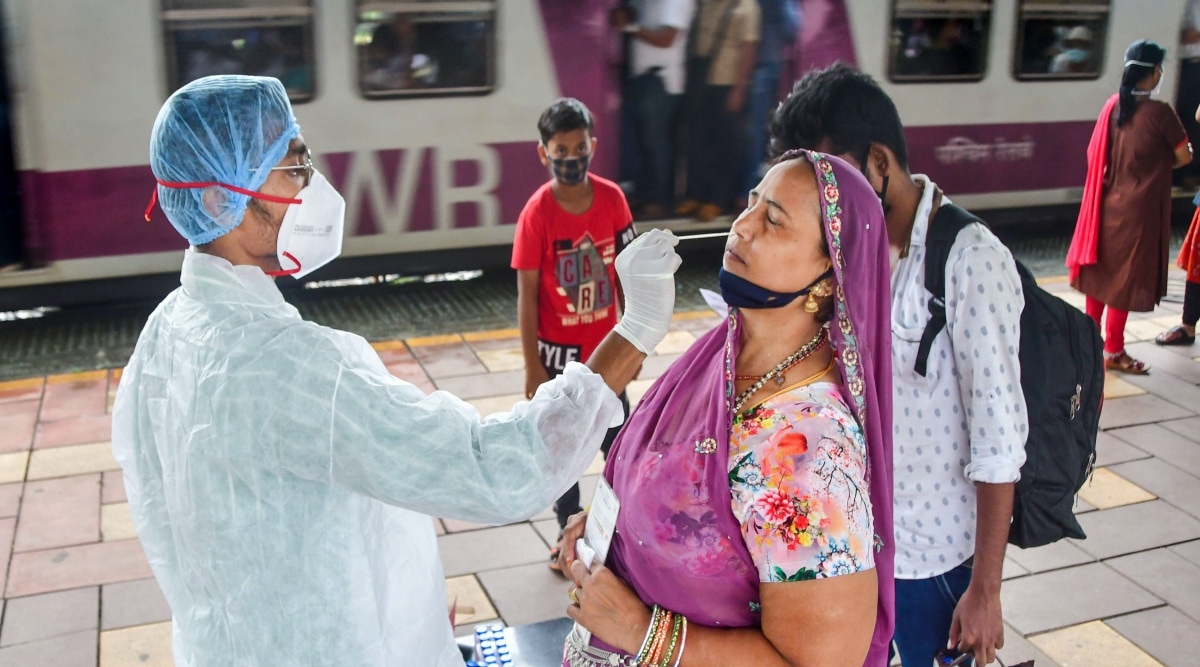 A BMC health worker collects swab samples of a passenger for COVID-19 test, at Dadar station, in Mumbai (PTI Photo)
