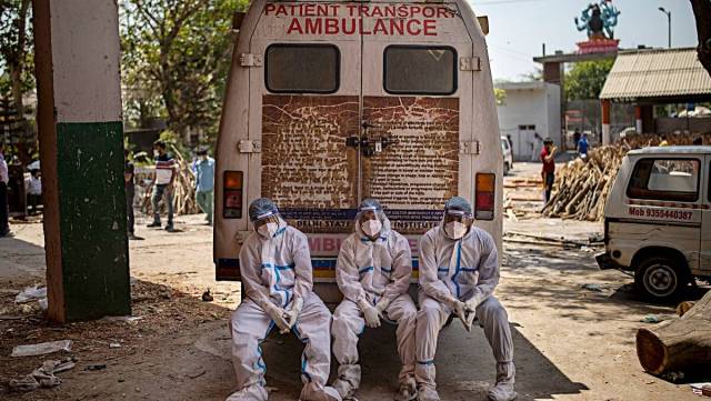 Exhausted workers who carried the dead for cremation sit on the rear step of an ambulance in New Delhi. (AP/ File)