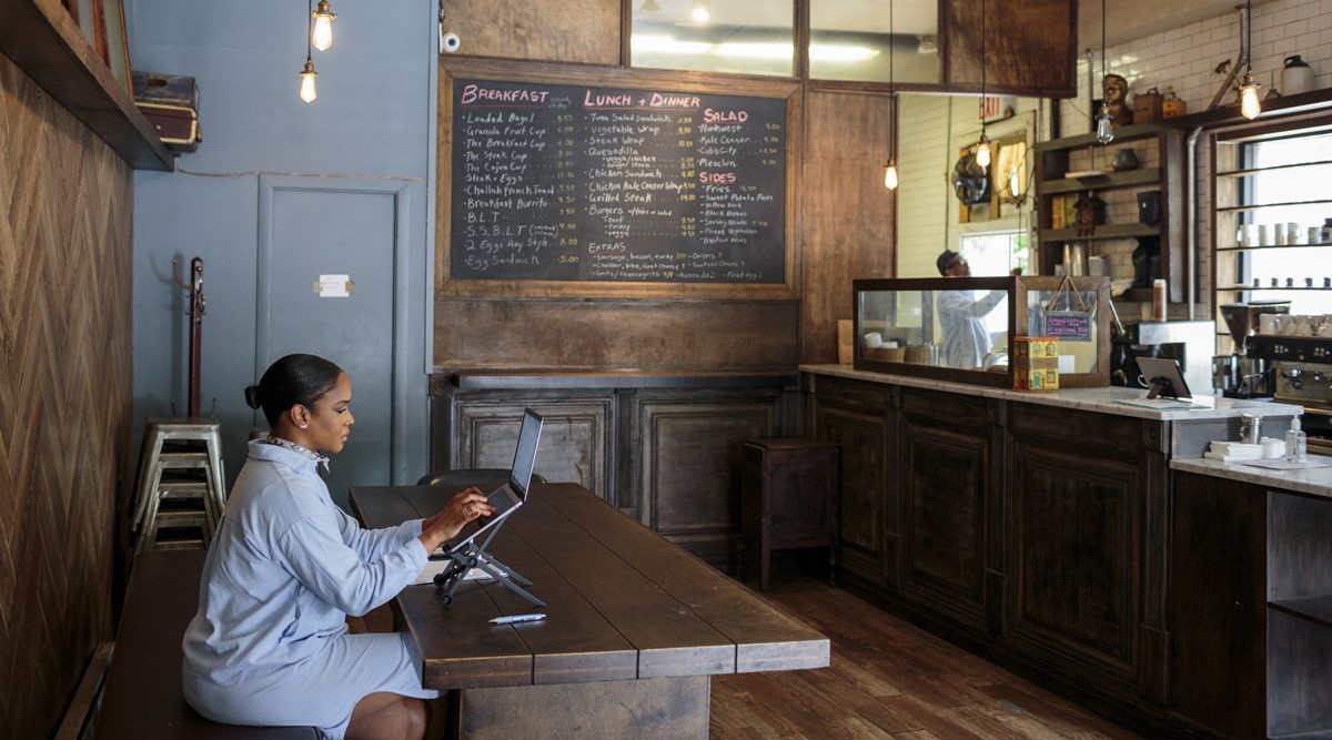Kia Roberts, an entrepreneur, works from Corner Grind Coffee Kitchen, a coffee shop in New York owned by her husband, July 12, 2021. As the office world adjusts to a new normal and workers grow tired of their homes, WeWork and its competitors reap the benefits. (The New York Times)