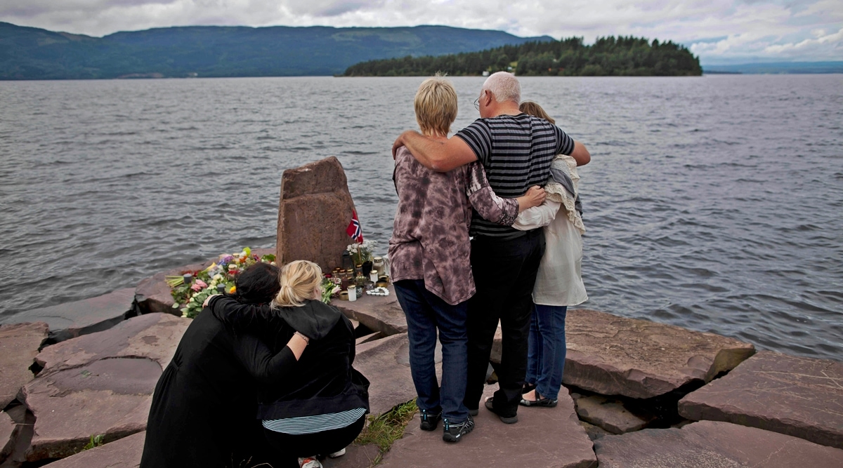 In this Monday, July 25, 2011 file photo, relatives of a victim gather to observe a minute's silence on a campsite jetty on the Norwegian mainland, across the water from Utoya island, seen in the background, where people have been placing floral tributes in memory of those killed in the shooting massacre on the island.  (AP)