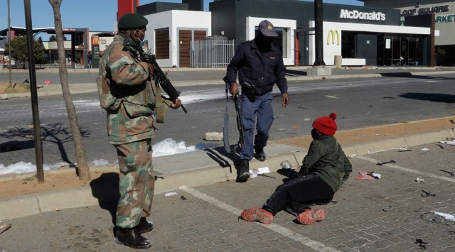 A policeman and soldier apprehend a looter at a shopping centre in Soweto, Johannesburg, Tuesday July 13, 2021. South Africa's rioting continued Tuesday with the death toll rising to 32 as police and the military struggle to quell the violence in Gauteng and KwaZulu-Natal provinces. The violence started in various parts of KwaZulu-Natal last week when Zuma began serving a 15-month sentence for contempt of court.  (AP Photo/Themba Hadebe)