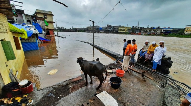 People look on from an elevated portion of an area submerged in flood waters, following heavy rain in Thane district. (Representational: PTI Photo)