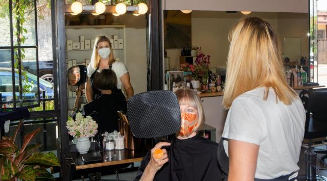 An employee and a customer both wear masks at a salon in Los Angeles, July 27, 2021. The CDC’s new masking advice was based in part on unpublished data showing that the virus can thrive in the airways of vaccinated people. (Alex Welsh/The New York Times)