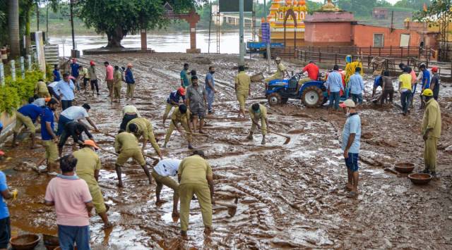 Municipal workers remove mud after the recession of flood-water at Krishnamai Ghat in Karad, Monday, July 26, 2021. (PTI Photo)