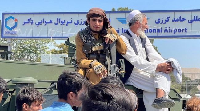 A member of Taliban forces (L) sits on a an armoured vehicle outside Hamid Karzai International Airport in Kabul, Afghanistan August 16, 2021. (Reuters)
