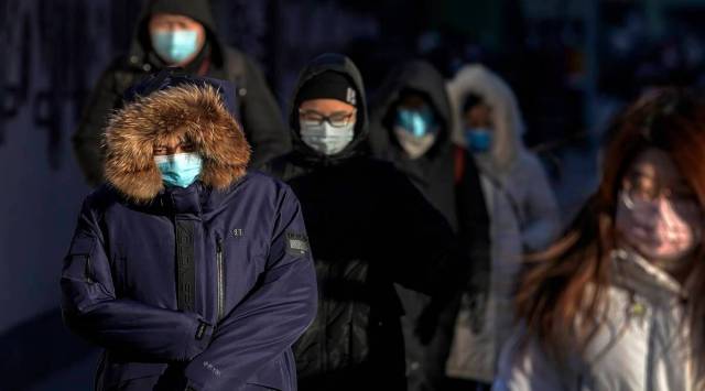 People wearing face masks to help curb the spread of the coronavirus head to work as the capital city is hit by cold wind in Beijing. (AP)
