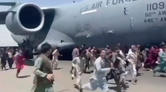 Some hundreds of people run alongside a U.S. Air Force C-17 transport plane as it moves down a runway of the international airport, in Kabul (AP)