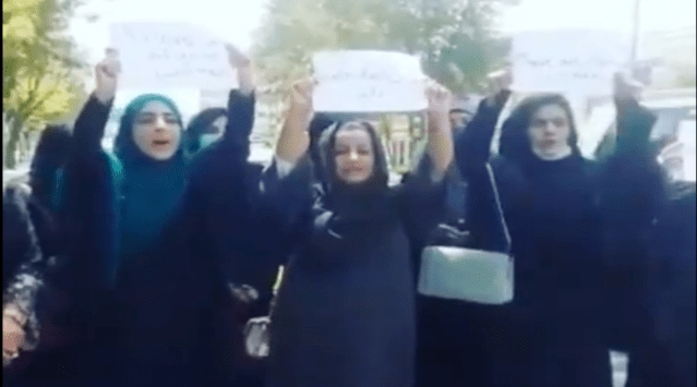Four women in black abayas and hijabs were seen holding up signs and shouting slogans even as armed men patrolled nearby. (Screengrab: Twitter/@leahmcelrath)