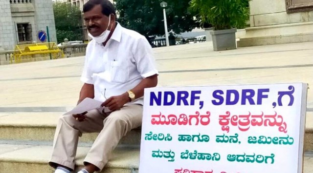 M P Kumaraswamy was seen with a placard demanding CM Bommai to release NDRF and SDRF funds for Mudigere and to compensate those who lost homes, land and crops in his constituency. (Photo credits: Special Arrangement)