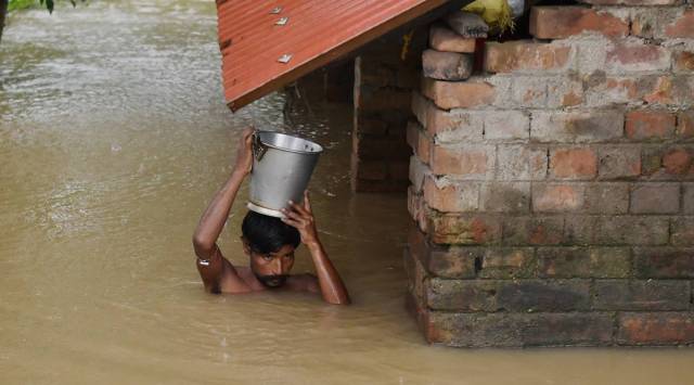 A man comes out with his belongings after his house submerged in flood water at Udaynarayanpur in Howrah district. (PTI)