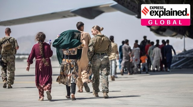 A Marine with the 24th Marine Expeditionary Unit walks with a family during ongoing evacuations at Hamid Karzai International Airport, Kabul, Afghanistan, Tuesday, Aug. 24, 2021. (Sgt. Samuel Ruiz/US Marine Corps via AP)