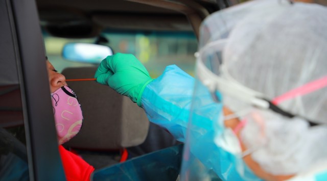 A health care worker administers a COVID-19 test at a drive-thru testing site in Oakland. (The New York Times/File)