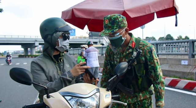 An army soldier checks identifications at a COVID-19 lockdown checkpoint in Ho Chi Minh City, Vietnam, Monday, Aug. 23, 2021. Vietnam's largest metropolis Ho Chi Minh City has enabled a strict lockdown order to help curb the recent outbreak of the pandemic. (Vu Tien Luc/VNA via AP)