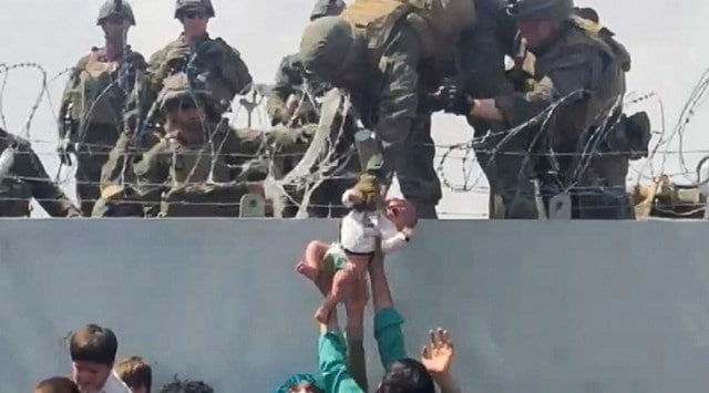 A baby is handed over to the American army over the perimeter wall of the airport for it to be evacuated, in Kabul, Afghanistan on Aug. 19, 2021. (Reuters)