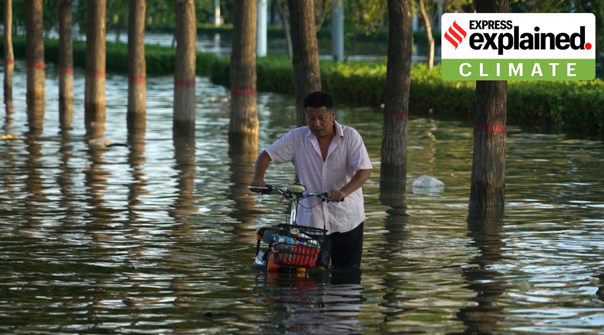 A man pushes a scooter through floodwaters in Xinxiang in central China's Henan Province, Monday, July 26, 2021. (AP Photo/Dake Kang, File)