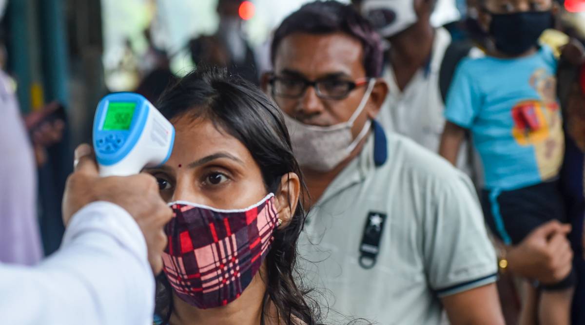 A BMC health worker does thermal screening of a passenger for COVID-19 test, at Dadar railway station in Mumbai, Wednesday, Aug. 18, 2021. (PTI Photo)